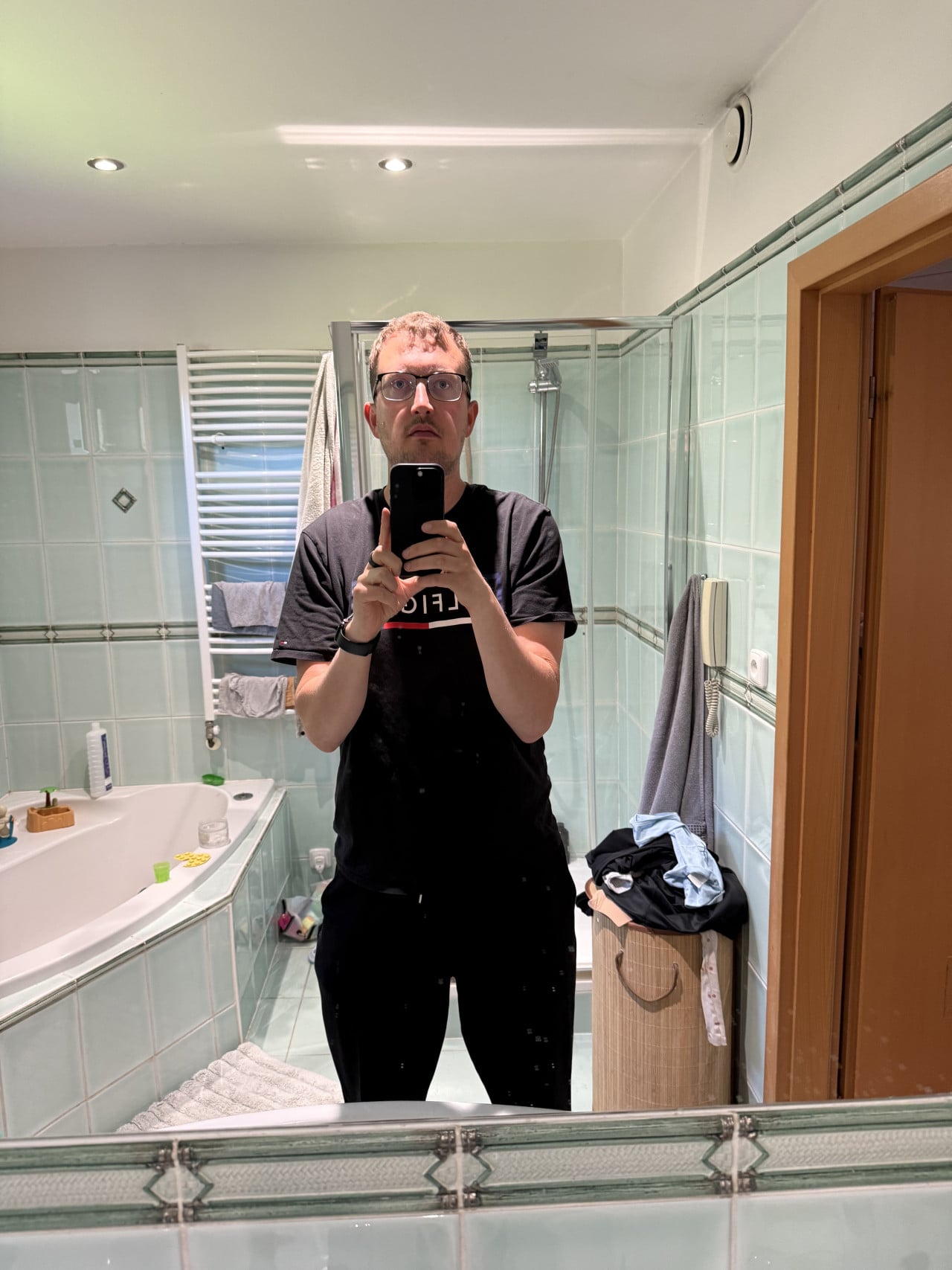 Muž v koupelně pořizuje selfie před zrcadlem po laserové operaci očí.