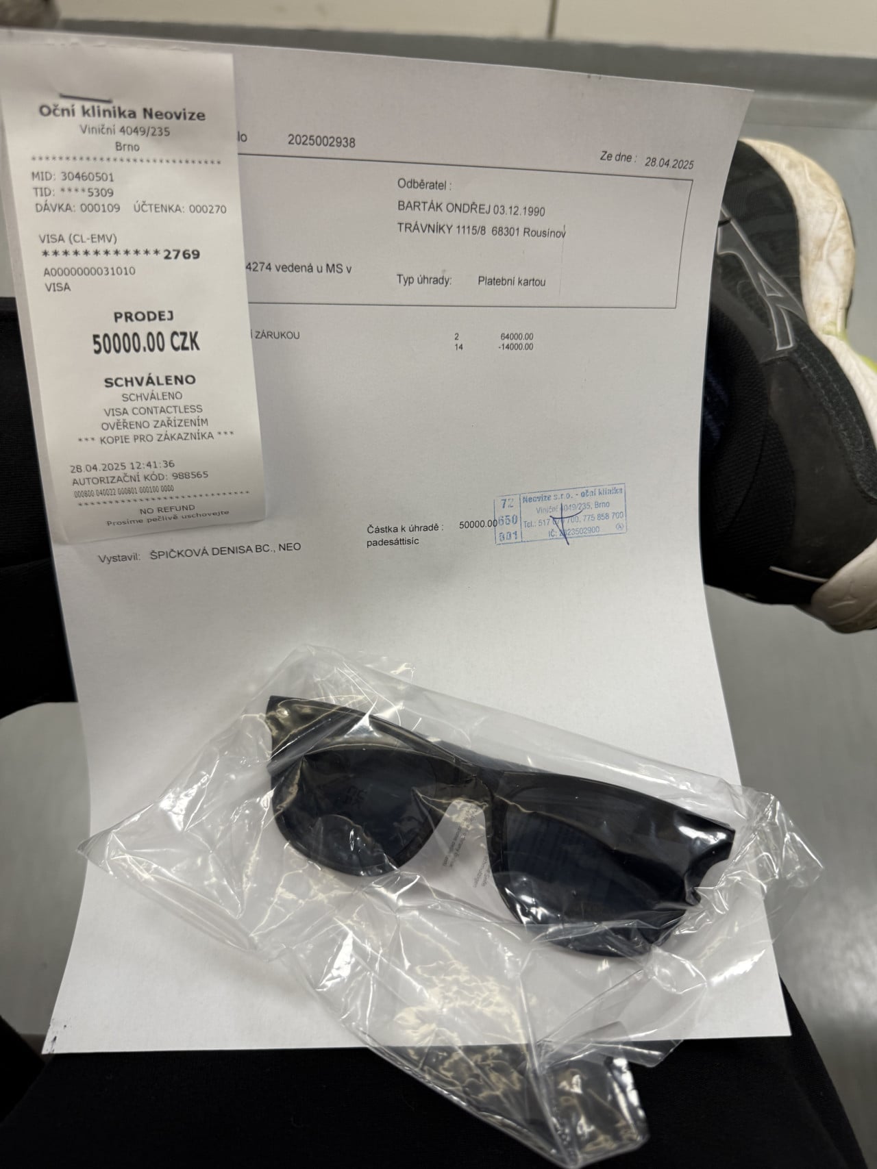 Účtenka, lékařský doklad a zabalené sluneční brýle na stole