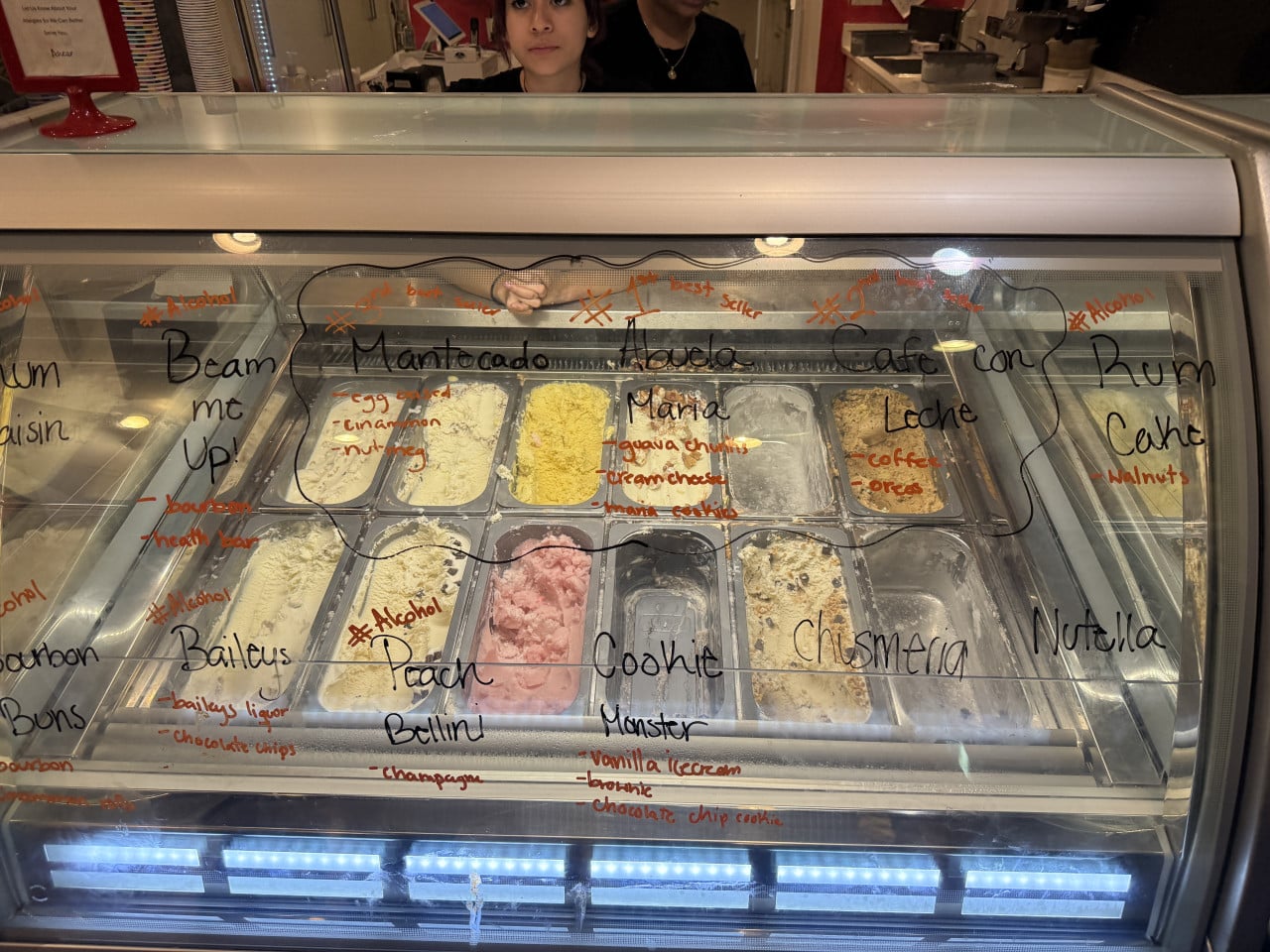 Vitrína se zmrzlinou, na skle nápisy Mantecado, Mango, Cookie Monster, Nutella, Rum Cake