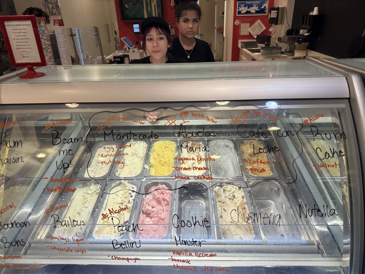 Dvě prodavačky za vitrínou se zmrzlinou, nápisy Mantecado, Abuela Maria, Cafe con Leche.