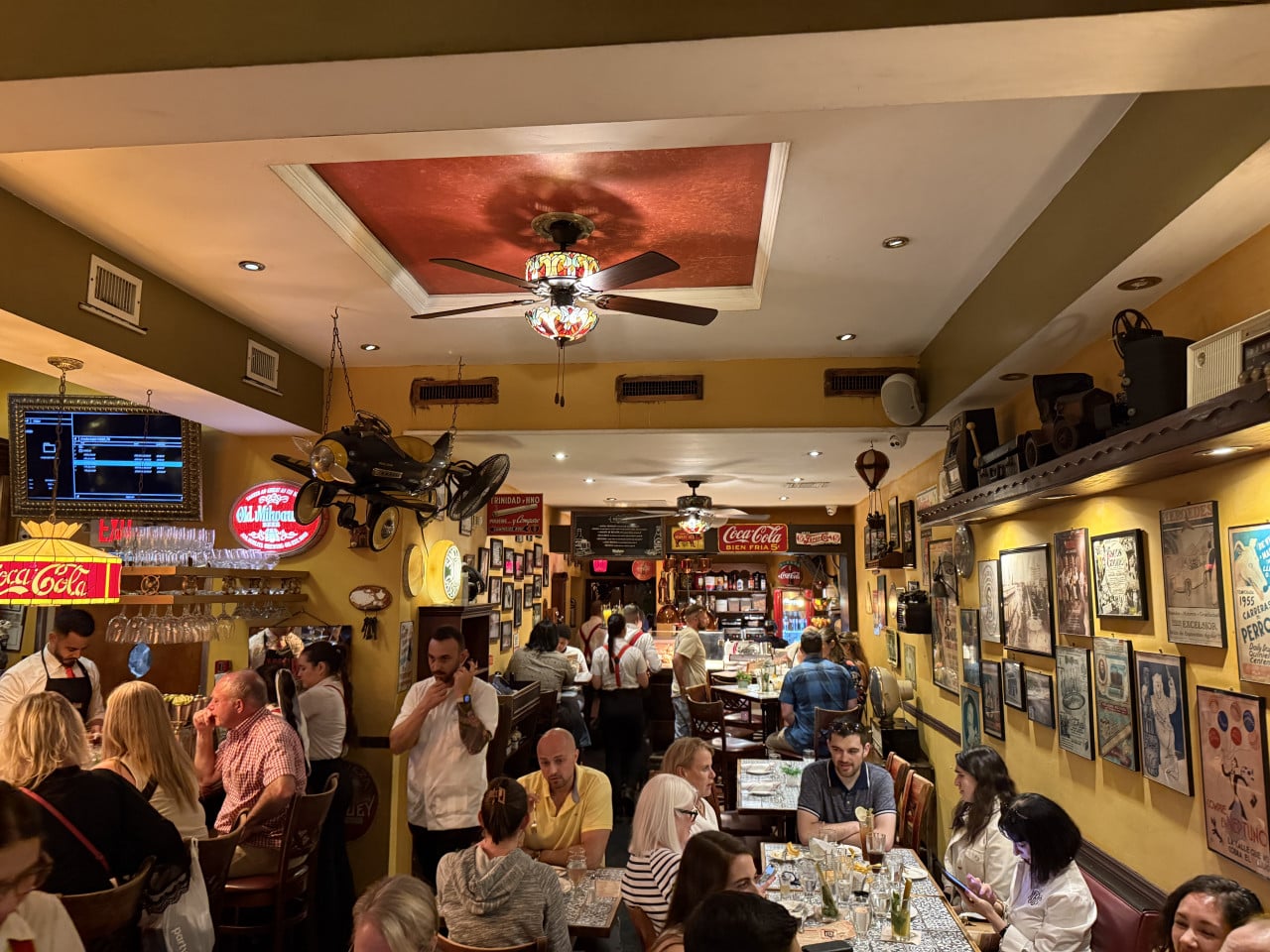 Přeplněná restaurace v Little Havana, žluté stěny, motorka, nápisy Coca-Cola, EXIT.