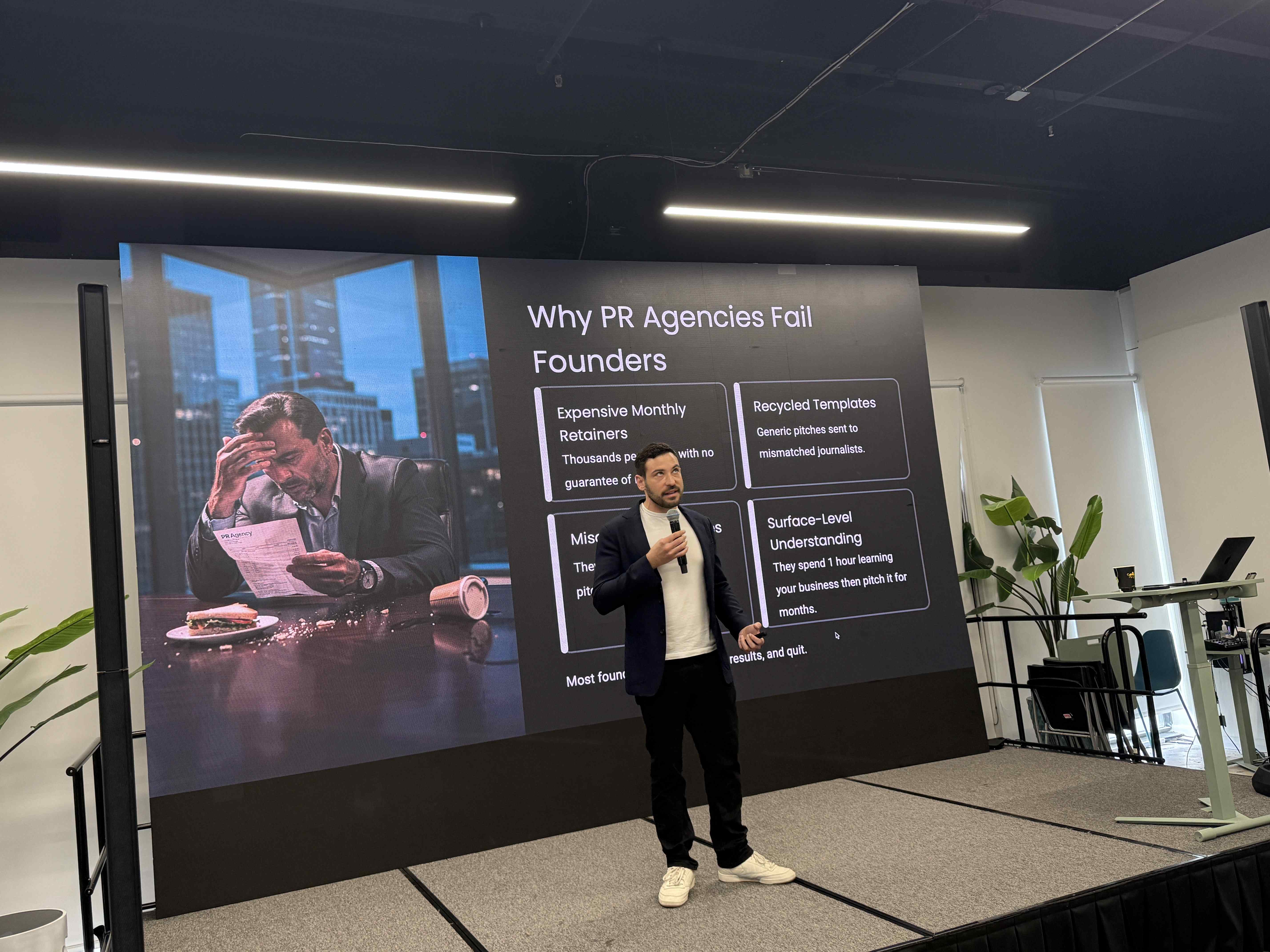 Speaker s mikrofonem před slide Why PR Agencies Fail Founders na pódiu