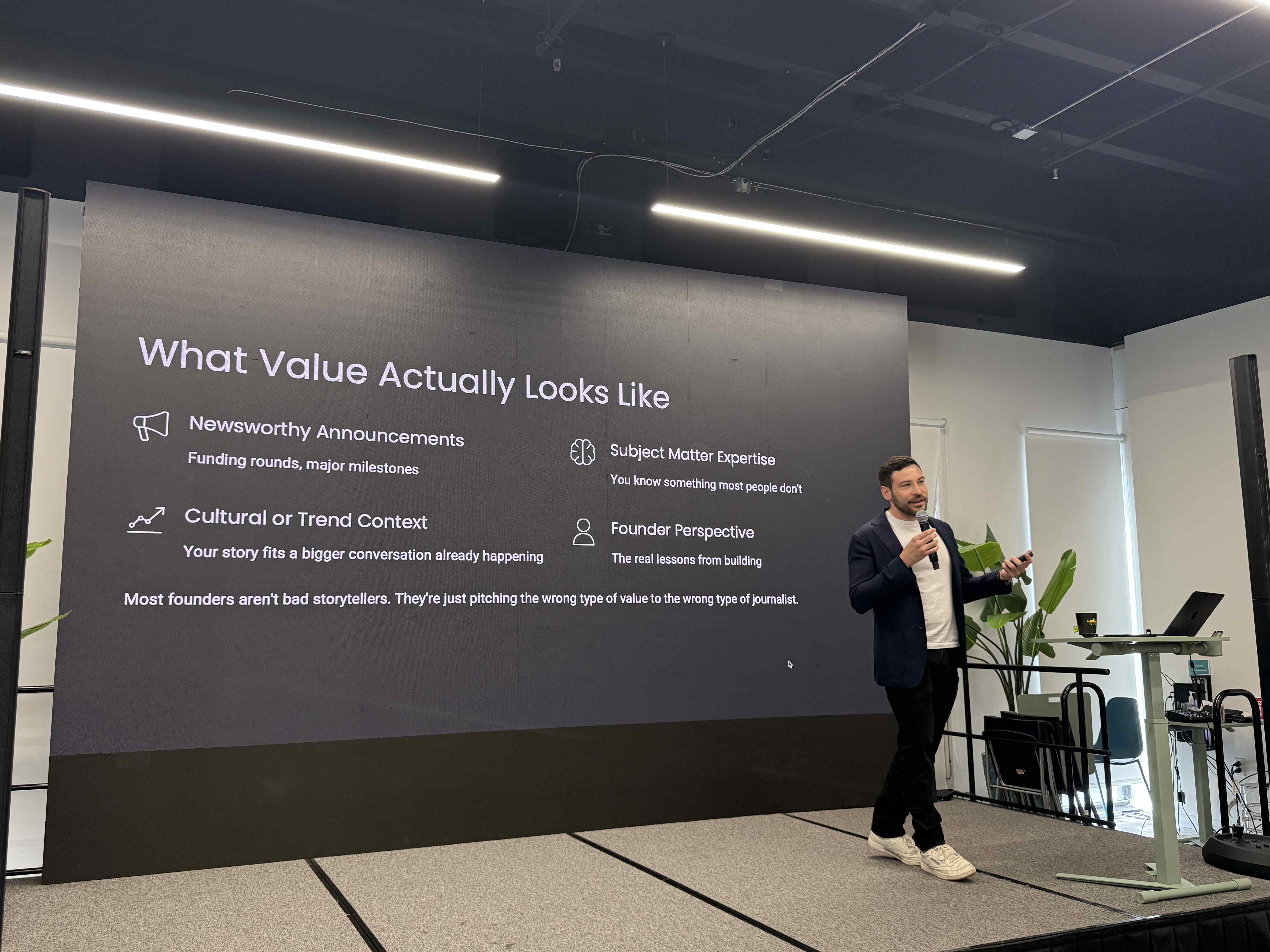 Speaker s mikrofonem před slide What Value Actually Looks Like na konferenčním pódiu.