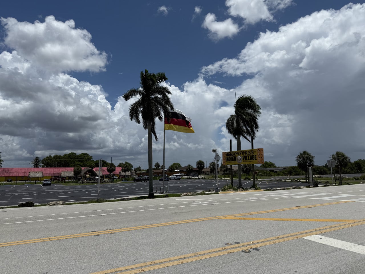 Parkoviště s palmami, vlajkou a nápisem Miccosukee Indian Village.