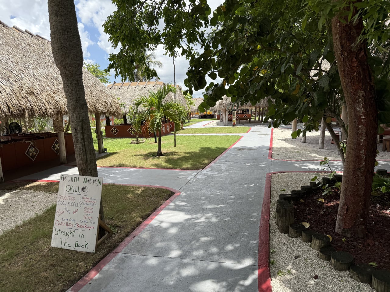 Miccosukee vesnice s doškovými chatami, palmami a cedulí Fourt Moon Grill.