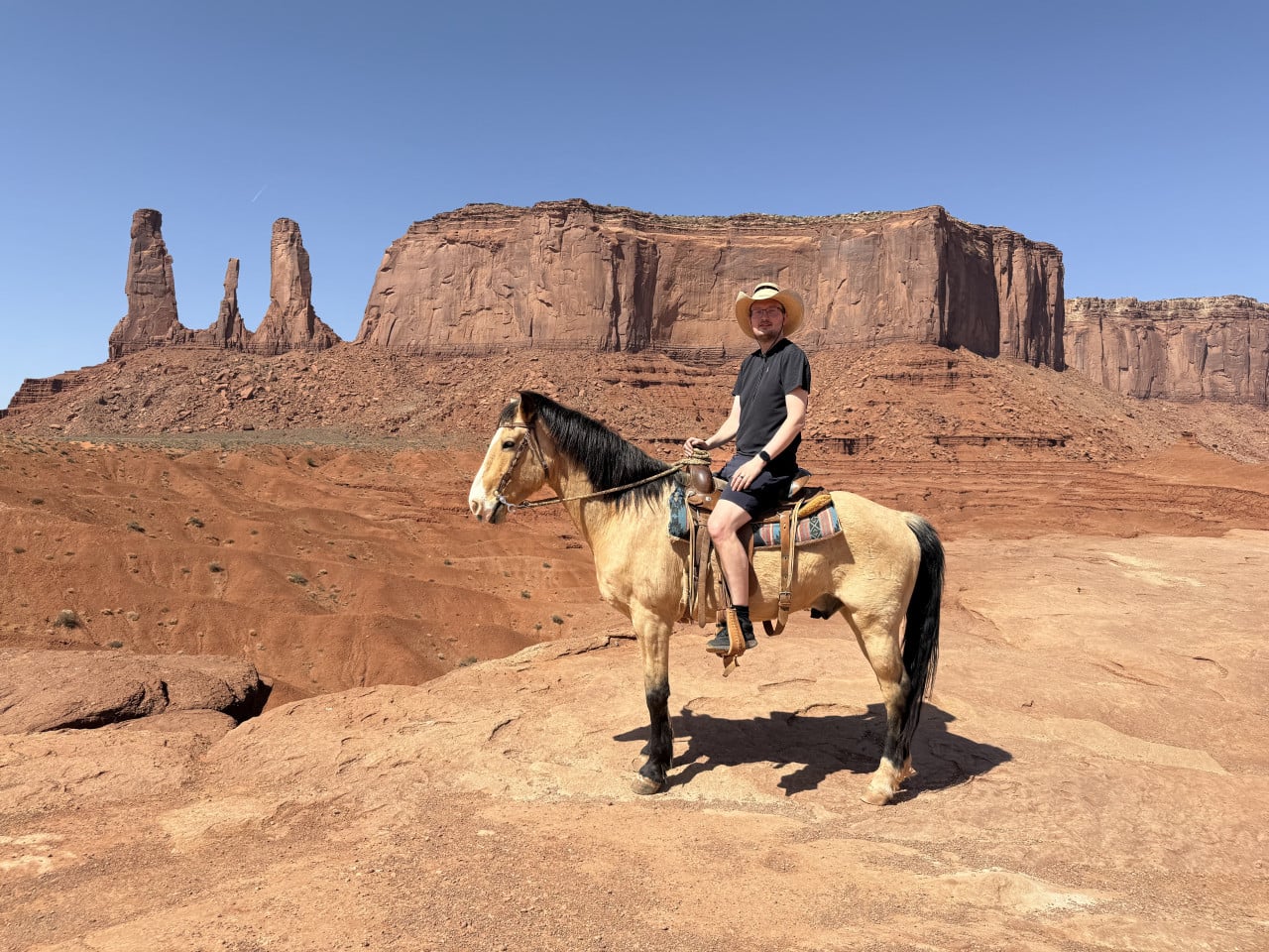 Muž v klobouku sedí na koni před skalními monumenty Monument Valley