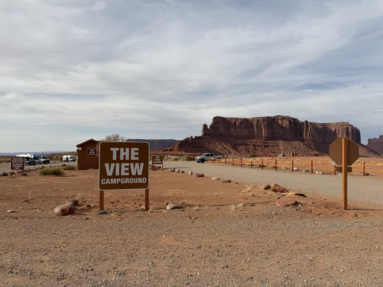 Cedule THE VIEW CAMPGROUND, parkoviště a skalní masiv Monument Valley v pozadí.