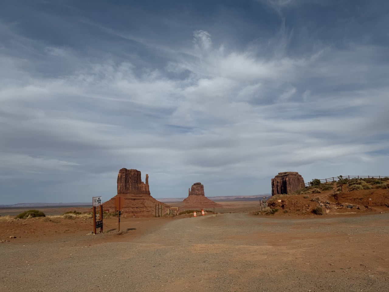 Prašná cesta v Monument Valley, skály v dálce a cedule NO DRONE ZONE