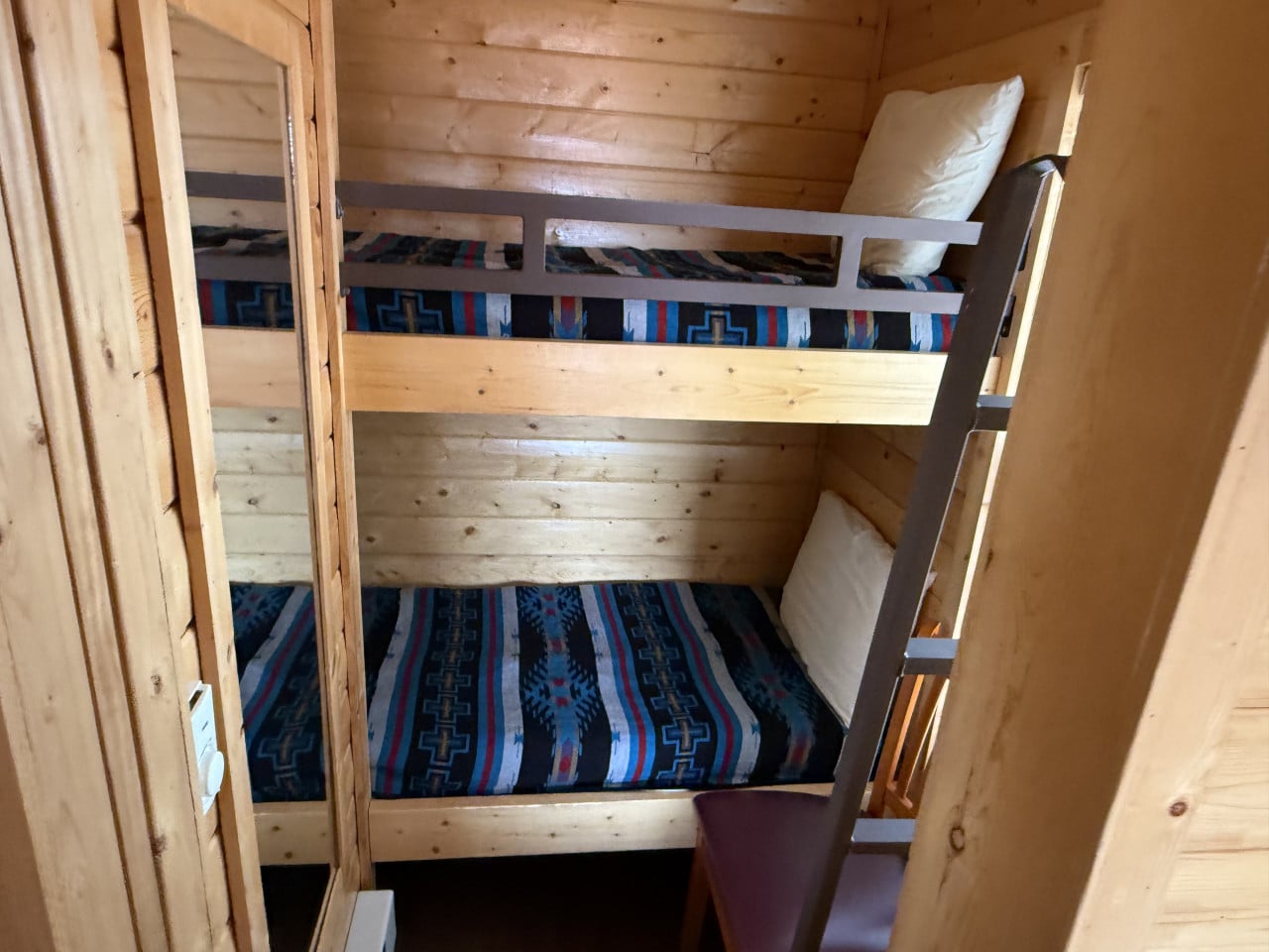 Palanda v dřevěné chatce, žebřík, zrcadlo, barevné přikrývky a polštáře
