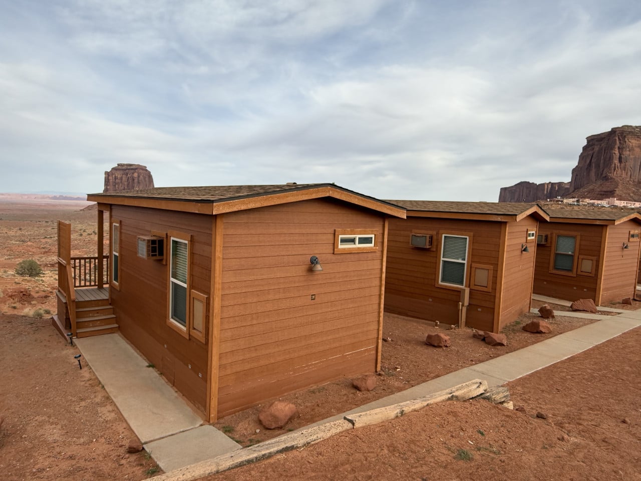 Dřevěné chatky v poušti, v pozadí skalní monumenty Monument Valley
