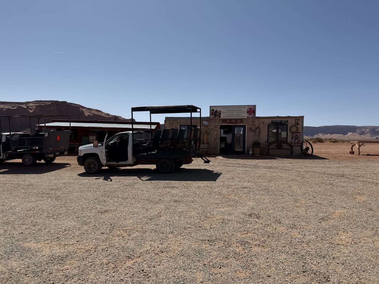 Turistický otevřený truck před obchodem Monument Valley’s Treasures, nápis Pottery na poušti.