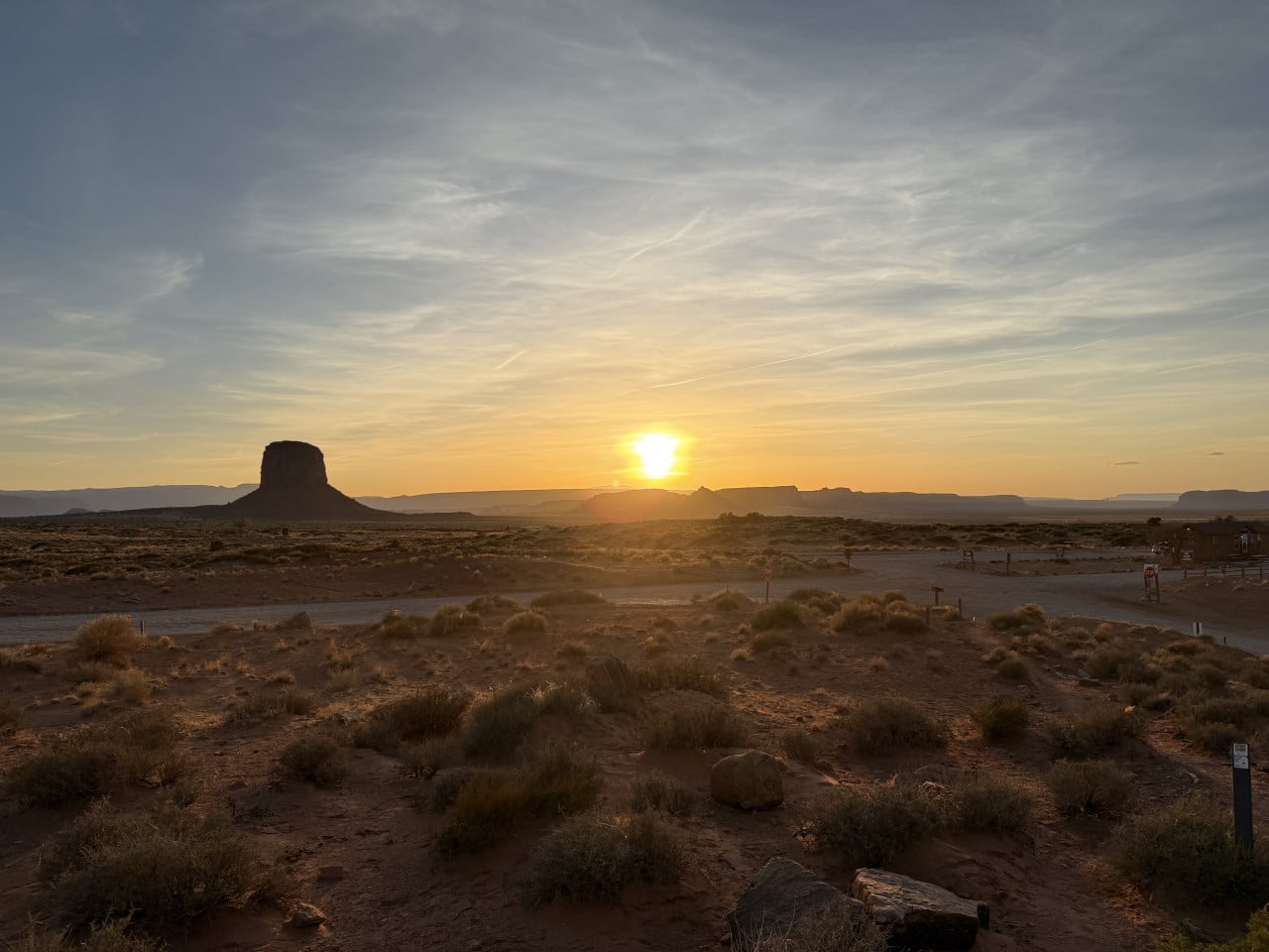 Západ slunce nad Monument Valley, silueta stolové hory, poušť a kemp