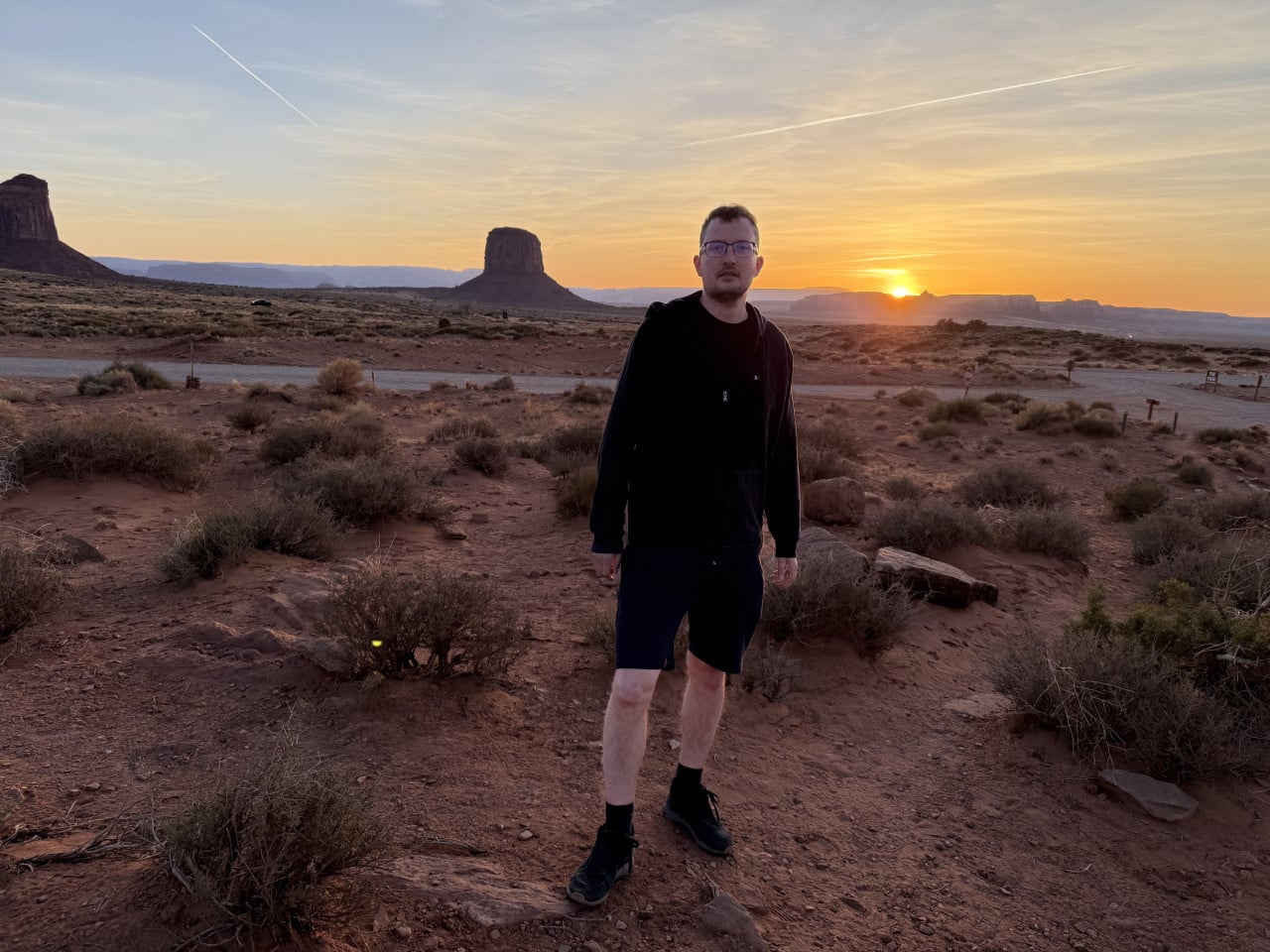 Muž v černé mikině stojí při západu slunce před stolovou horou