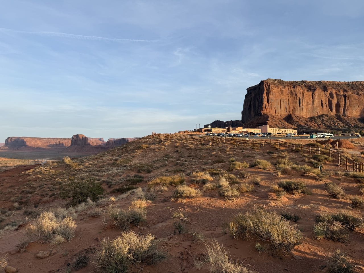 Budovy a parkoviště na okraji Monument Valley, pod červenou skalní stěnou
