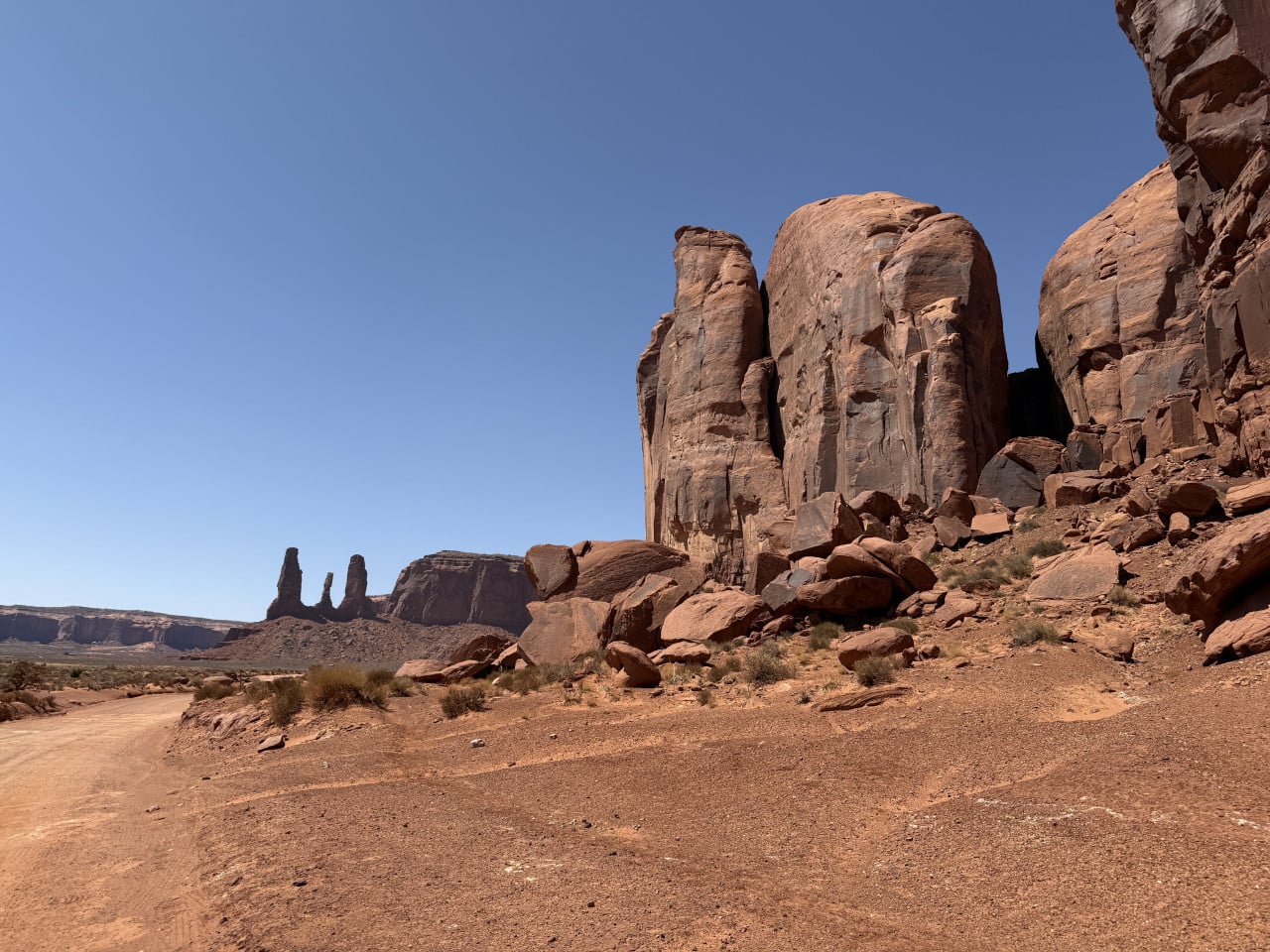 Prašná cesta a rudé skalní stěny Monument Valley, v dálce věže