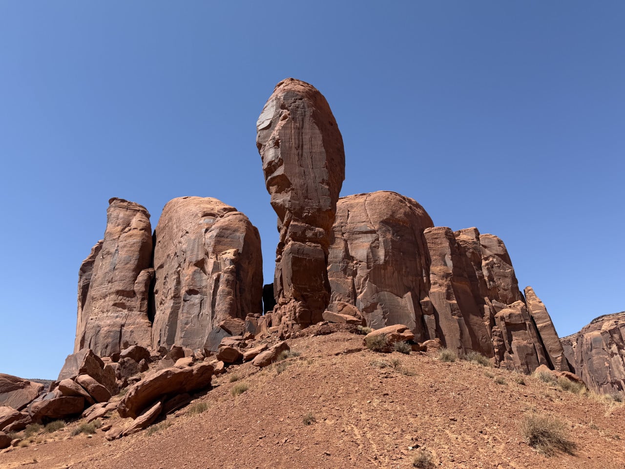 Masivní červené pískovcové skály v Monument Valley pod jasnou modrou oblohou