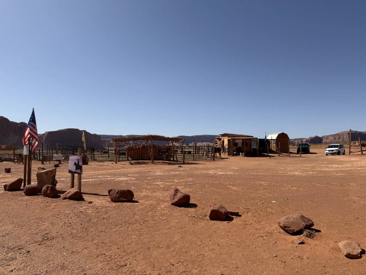 Pouštní ohrada s chatkami, americkou vlajkou a cedulí Hat Trail Rides