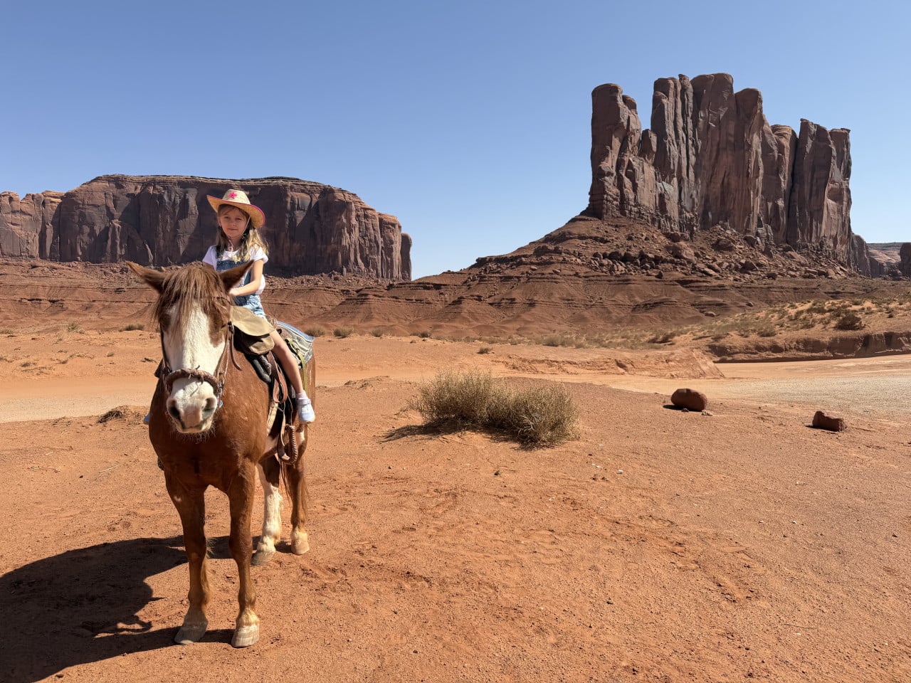 Dítě na koni v Monument Valley, v pozadí červené skalní věže.