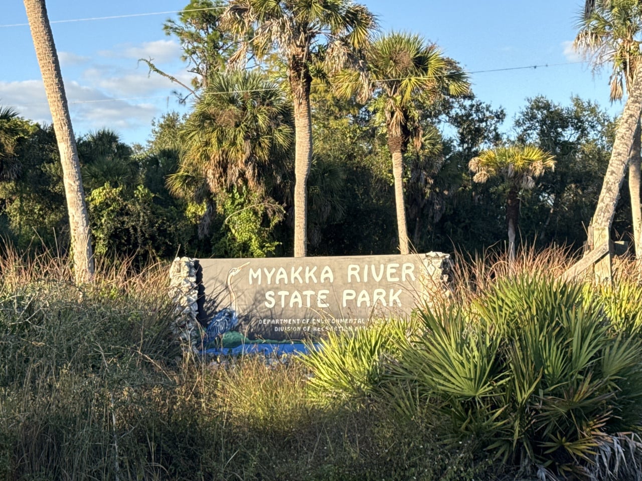 Vstupní cedule Myakka River State Park mezi palmami a hustou floridskou vegetací