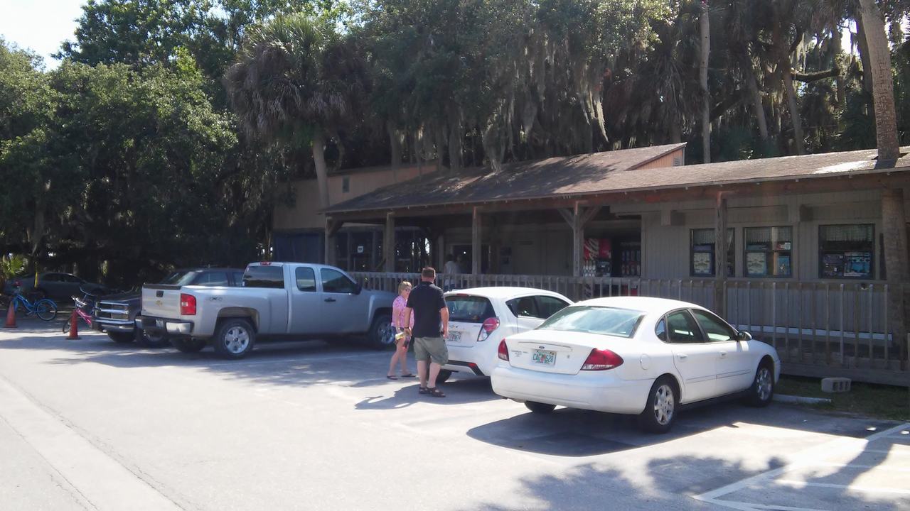 Parkoviště u návštěvnického centra v Myakka River State Park, zaparkovaná auta a lidé.