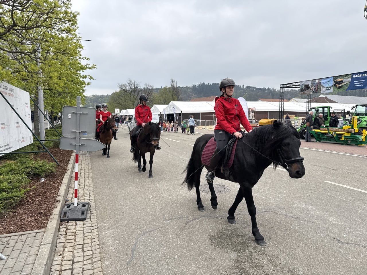 Jezdci v červených bundách na koních projíždějí výstavištěm BVV Brno.