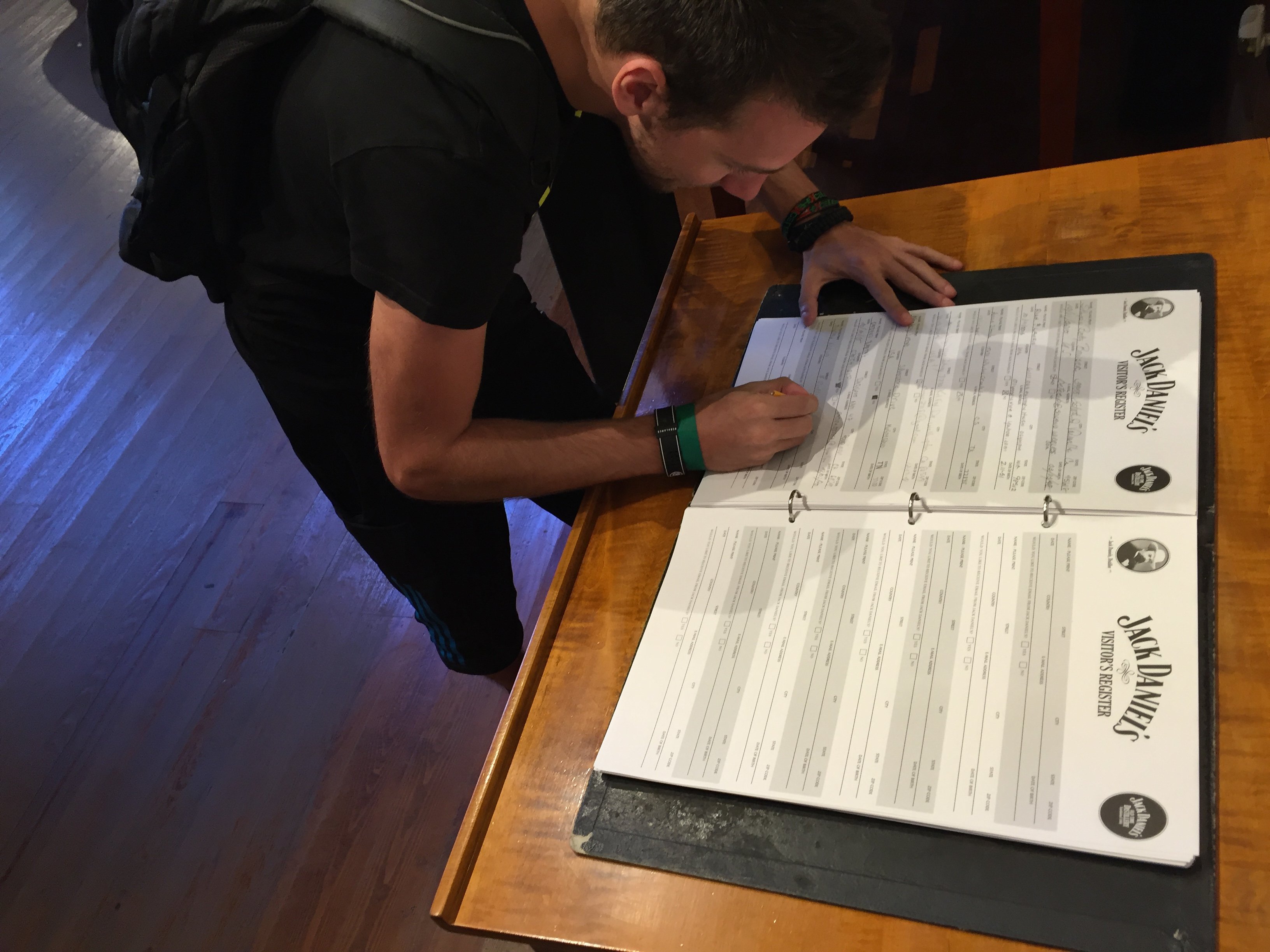 Muž vyplňuje knihu Jack Daniel's Visitors Register na dřevěném stole