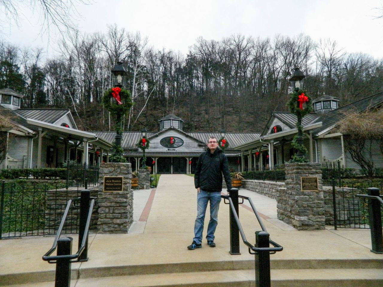 Muž před vchodem Jack Daniel’s Visitor Center, nápis Welcome, vánoční věnce