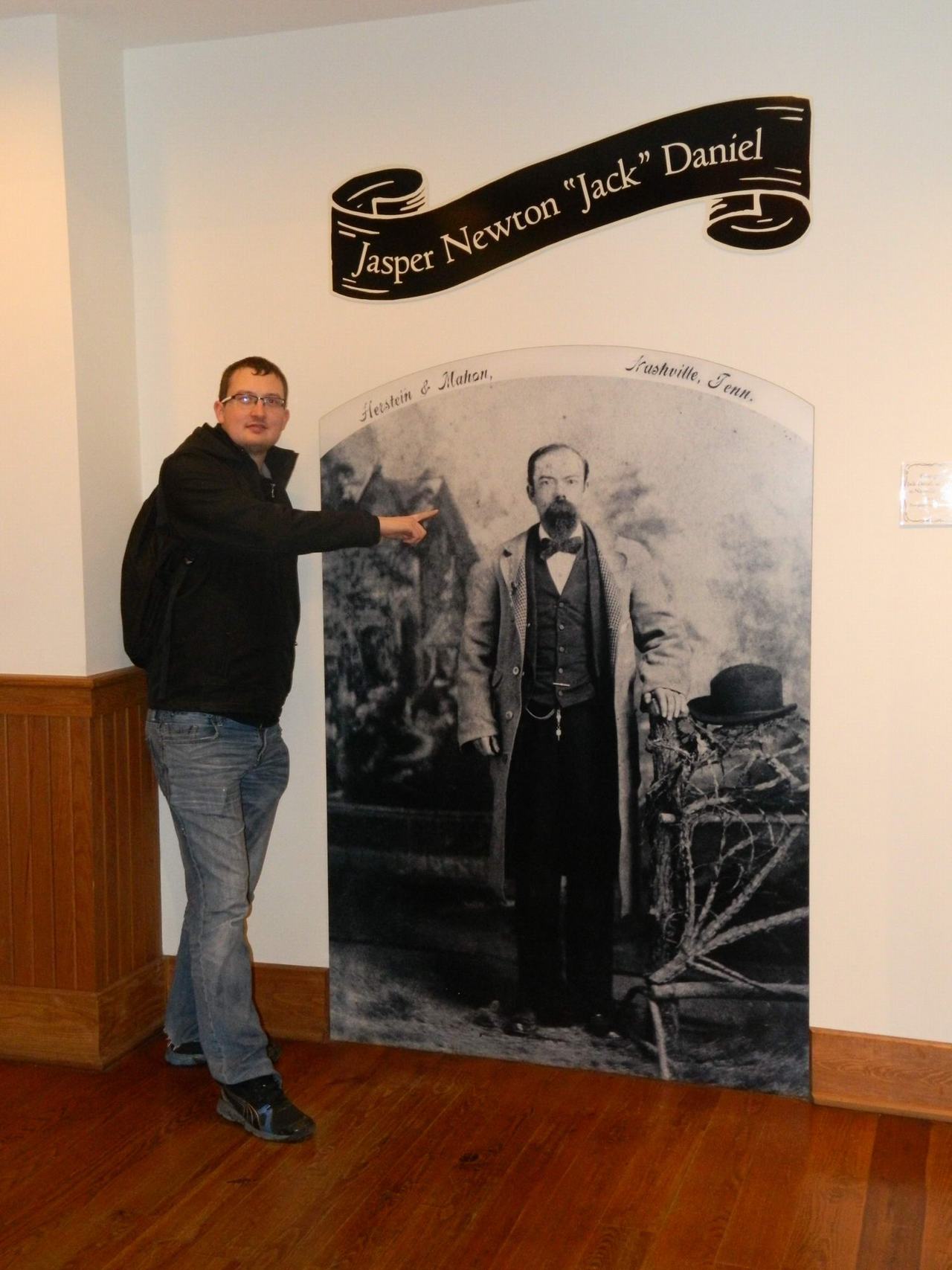 Muž ukazuje na historickou fotografii, nad ní nápis Jasper Newton Jack Daniel