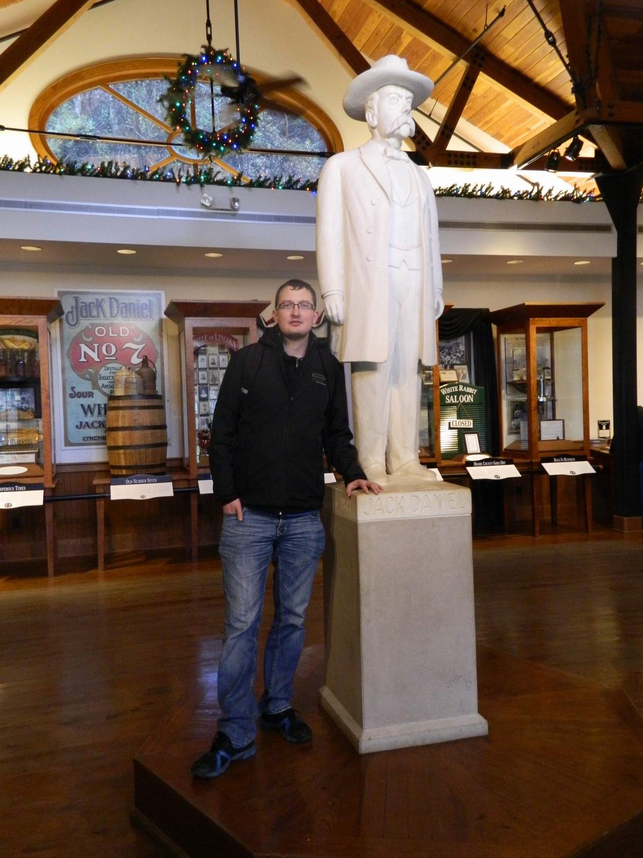 Muž u sochy Jack Daniel; v pozadí Jack Daniel’s Old No. 7, WHITE RABBIT SALOON.