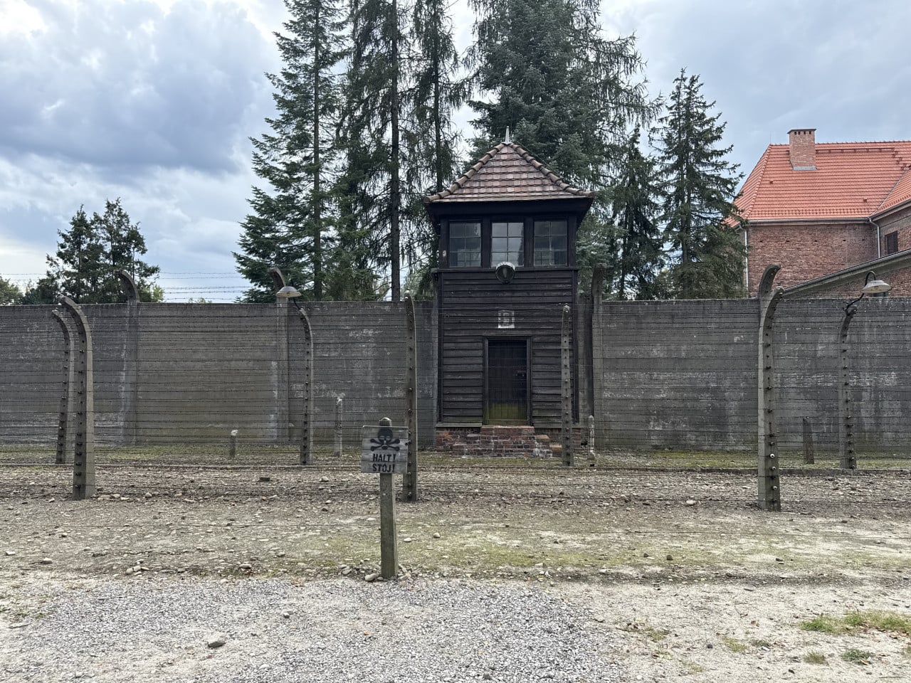 Strážní věž a plot s ostnatým drátem v Auschwitz-Birkenau, cedule HALT! STŮJ!