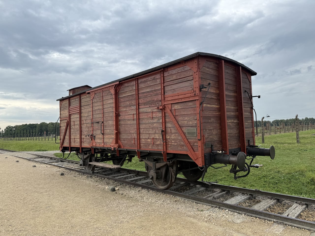 Historický nákladní vagón na kolejích v Auschwitz-Birkenau pod zamračenou oblohou