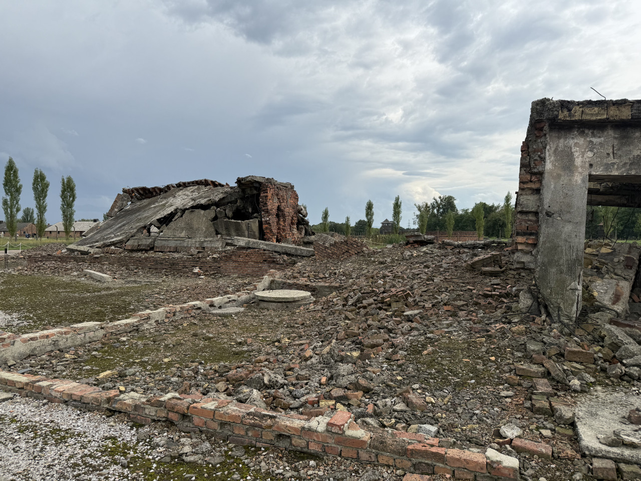 Ruiny zničených zděných budov v Auschwitz-Birkenau pod zataženou oblohou