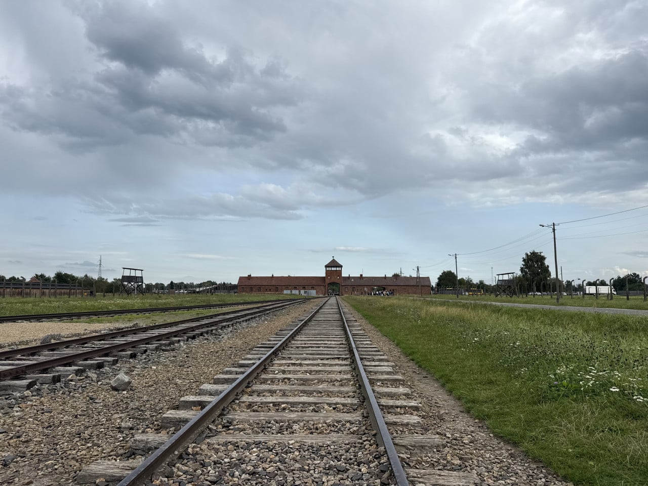 Železniční koleje vedoucí k bráně Auschwitz-Birkenau pod zamračenou oblohou