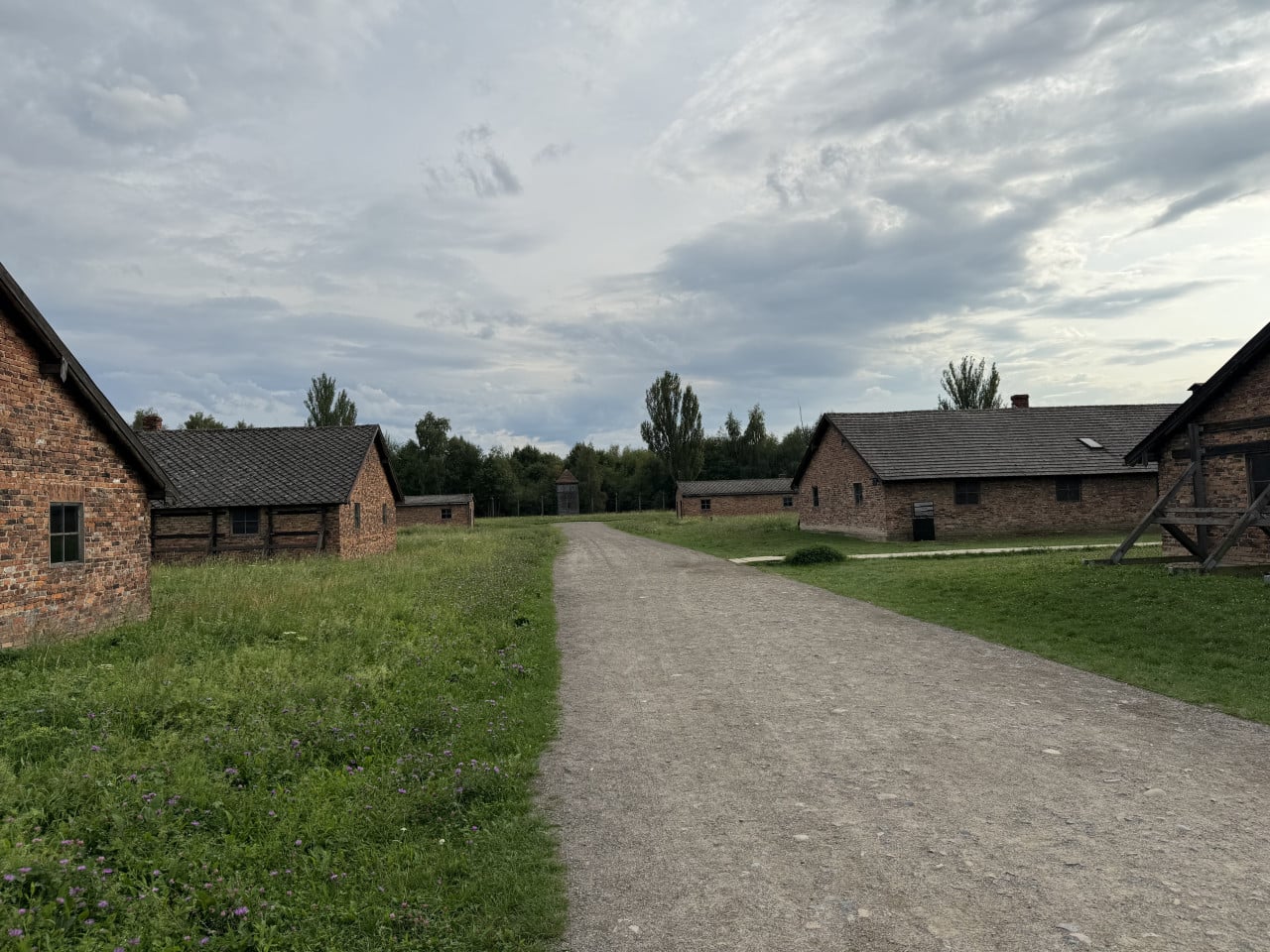 Pohled na cihlové baráky v Birkenau pod zamračenou oblohou.