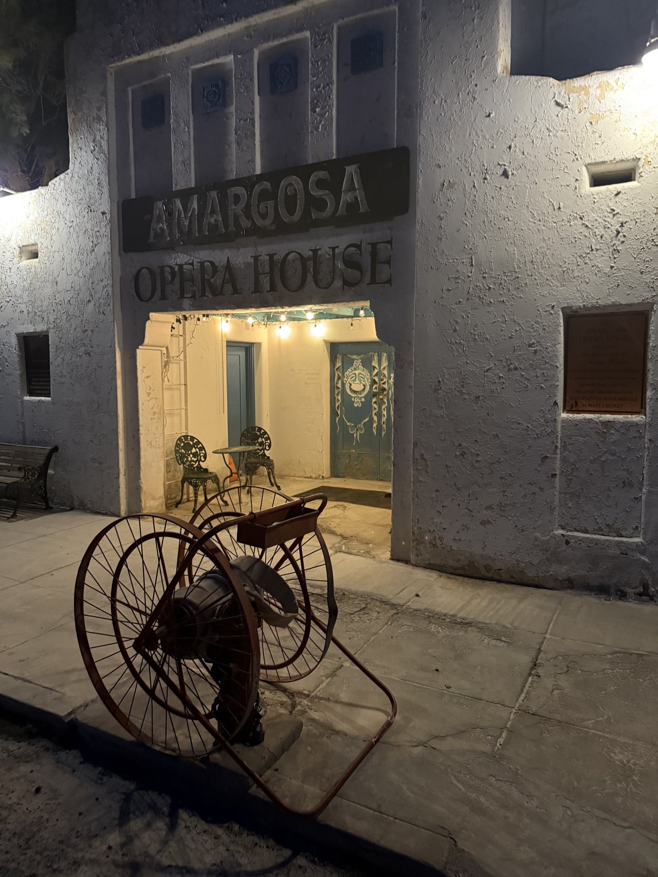 Noční vstup do Amargosa Opera House s nápisem a starým bicyklem venku