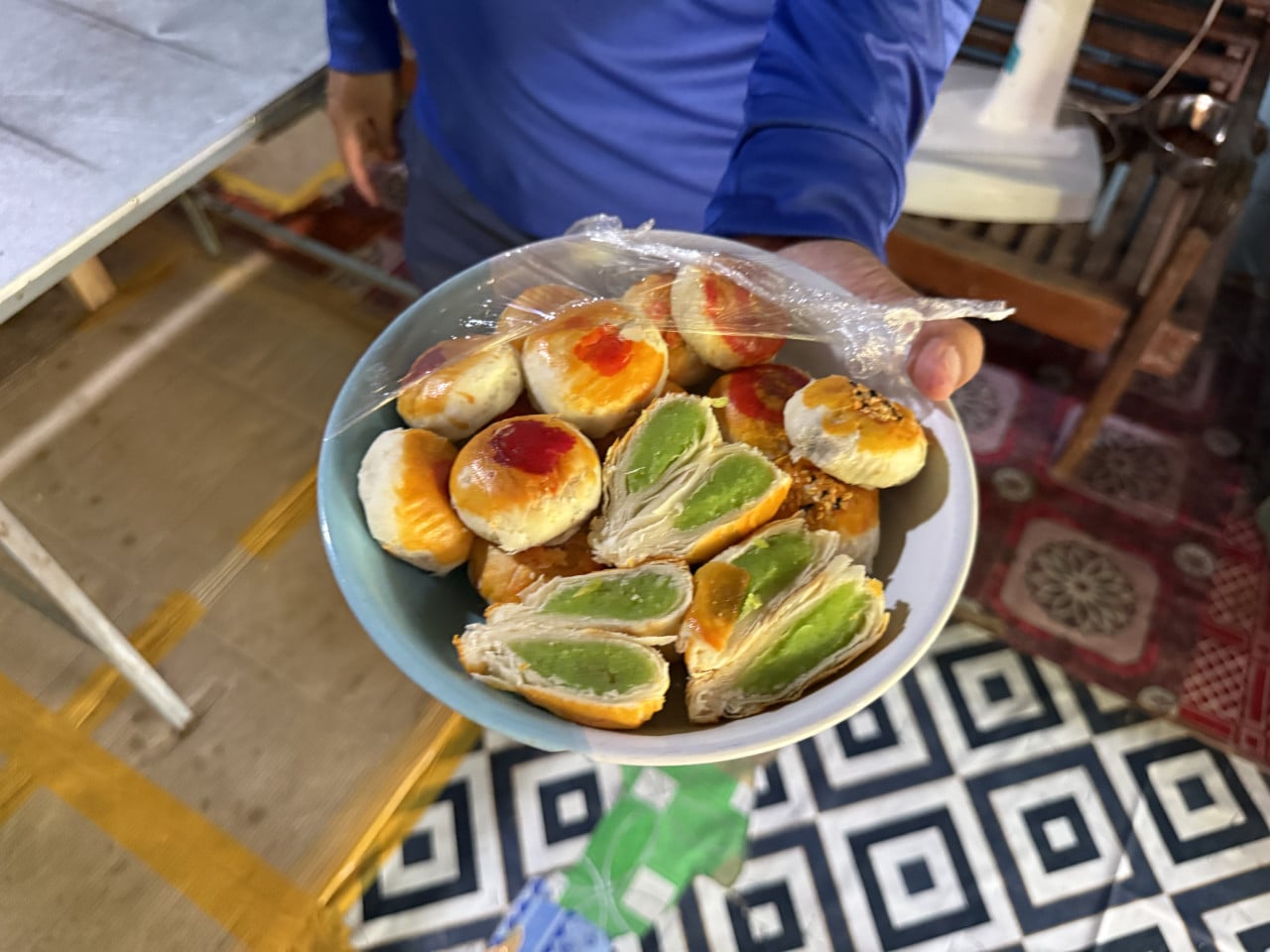 Místní drží mísu thajských koláčků, některé rozkrojené se zelenou náplní.