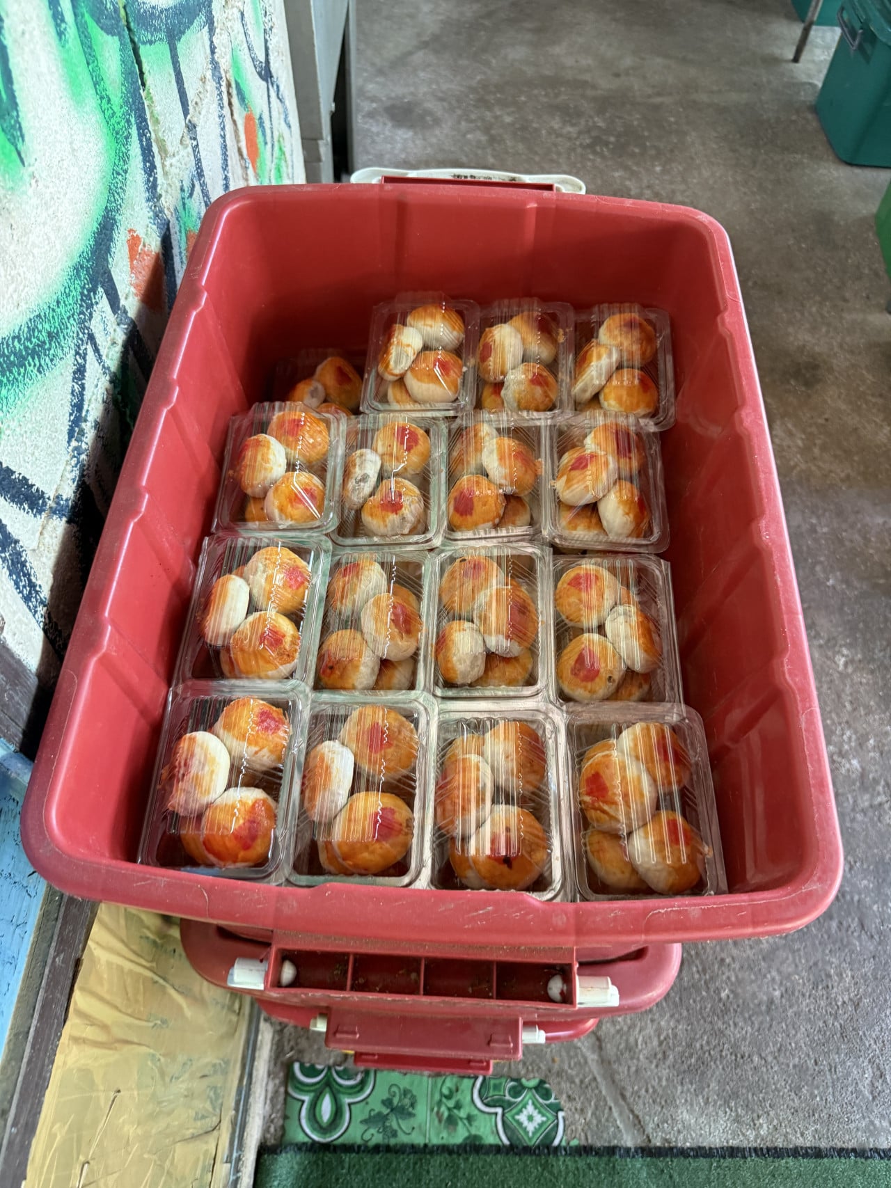 Červený plastový box plný balených koláčků v průhledných plastových krabičkách