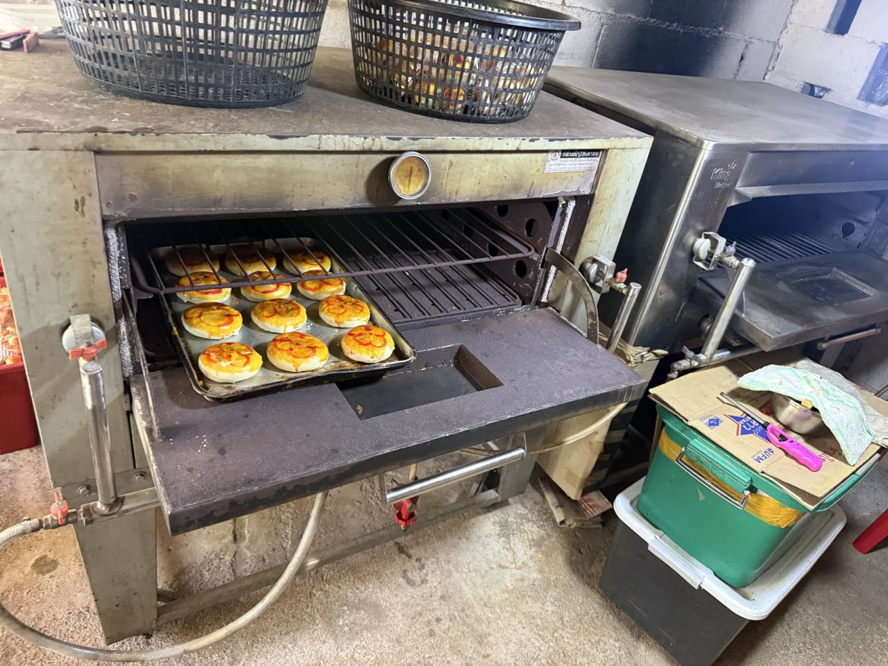 Otevřená pec na pečení s plechem thajských koláčků v rustikální výrobně.