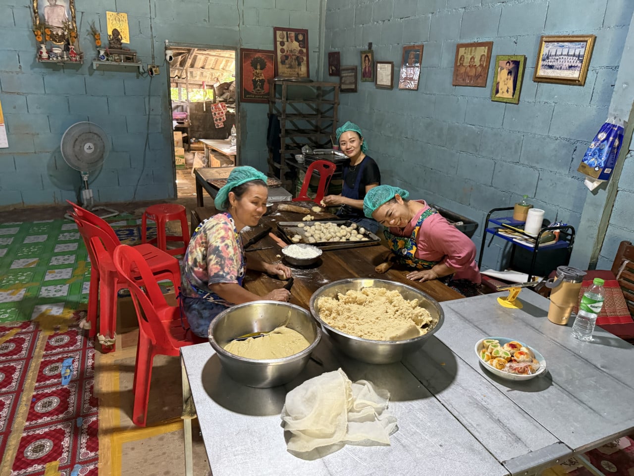 Tři ženy v síťkách připravují těsto a knedlíčky na stole v dílně