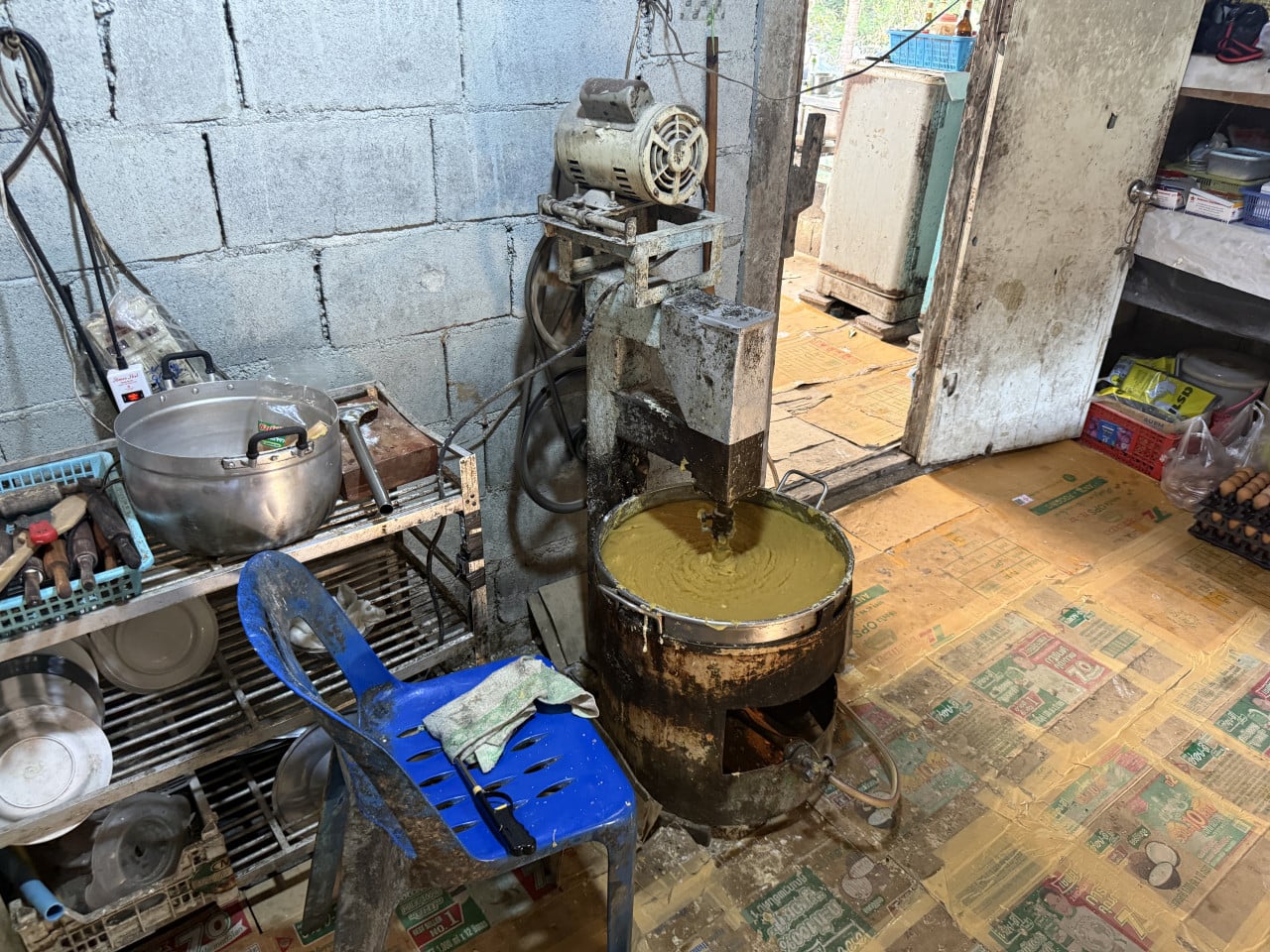 Stroj míchá žluté těsto ve velkém hrnci v provizorní kuchyni.