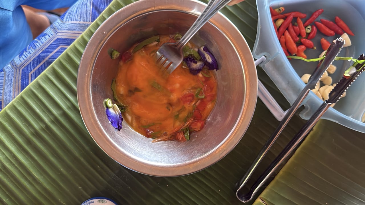 Kovová miska s rozšlehanými vejci, zeleninou a fialovými květy; vedle chilli, česnek