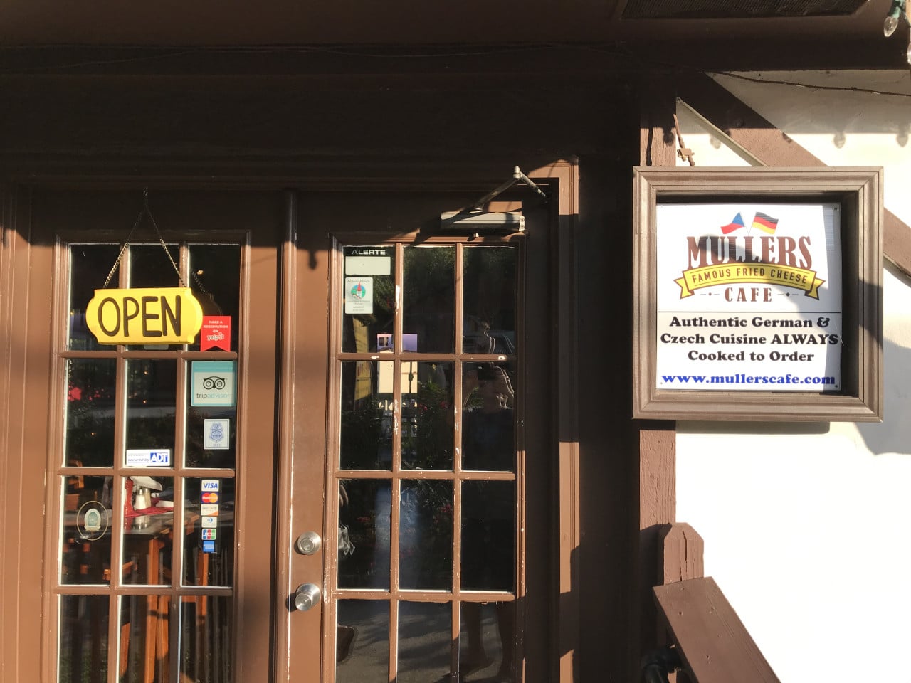 Vchod do restaurace s nápisem OPEN a cedulí Mullers Cafe, autentická německá a česká kuchyně