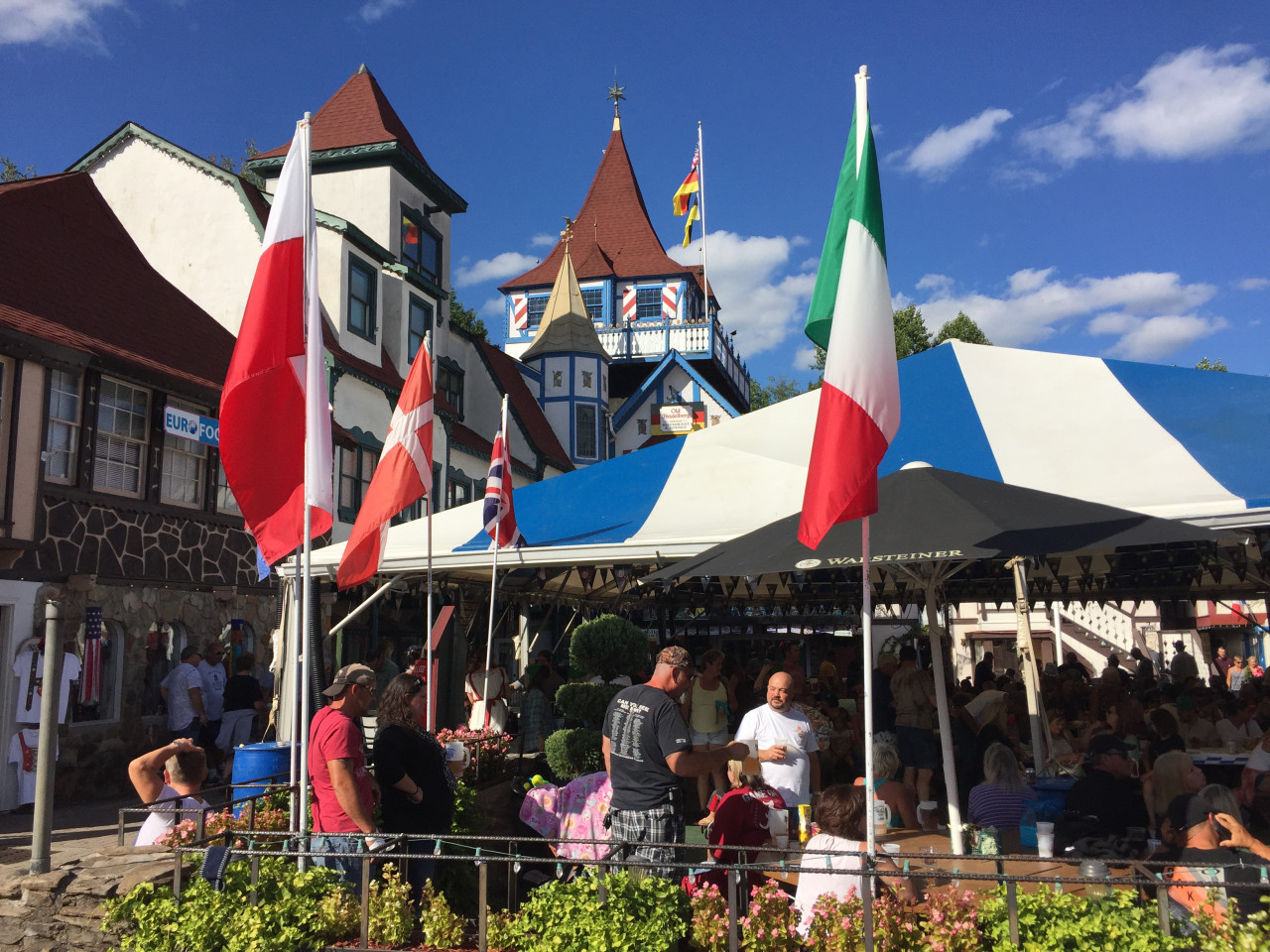 Lidé na Oktoberfestu v Helen, pod bavorsky laděnými domy a barevnými vlajkami