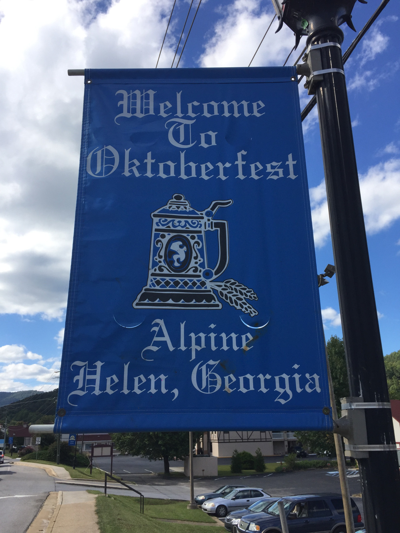 Modrá bannerová cedule Welcome To Oktoberfest, Helen, Georgia s pivním korbelem.