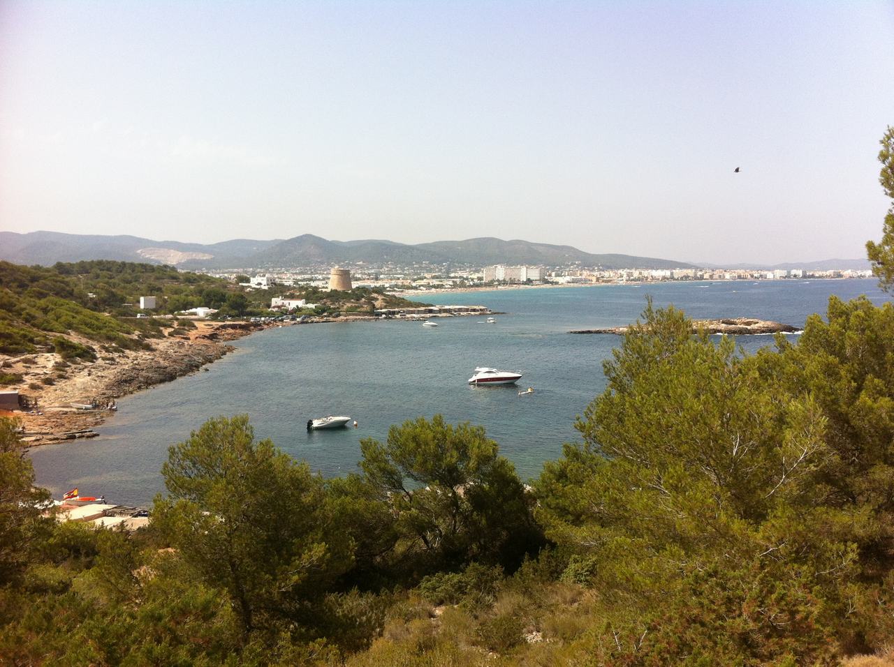 Panoramatický pohled na zátoku s loděmi, pobřežím, městem a kopci v dálce