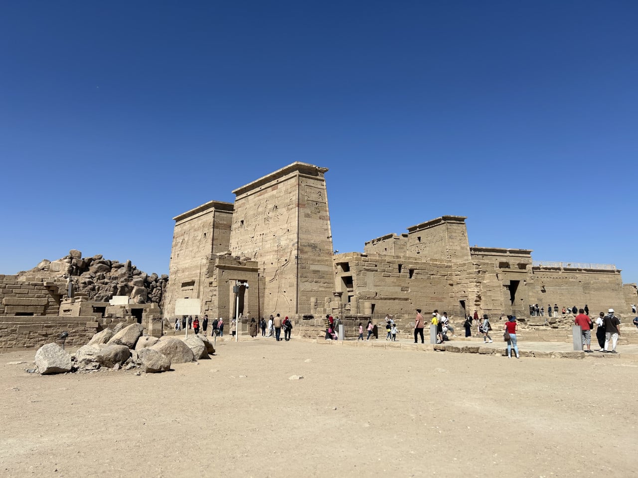 Chrámový komplex Philae s vysokými pískovcovými sloupy a turisty pod modrou oblohou