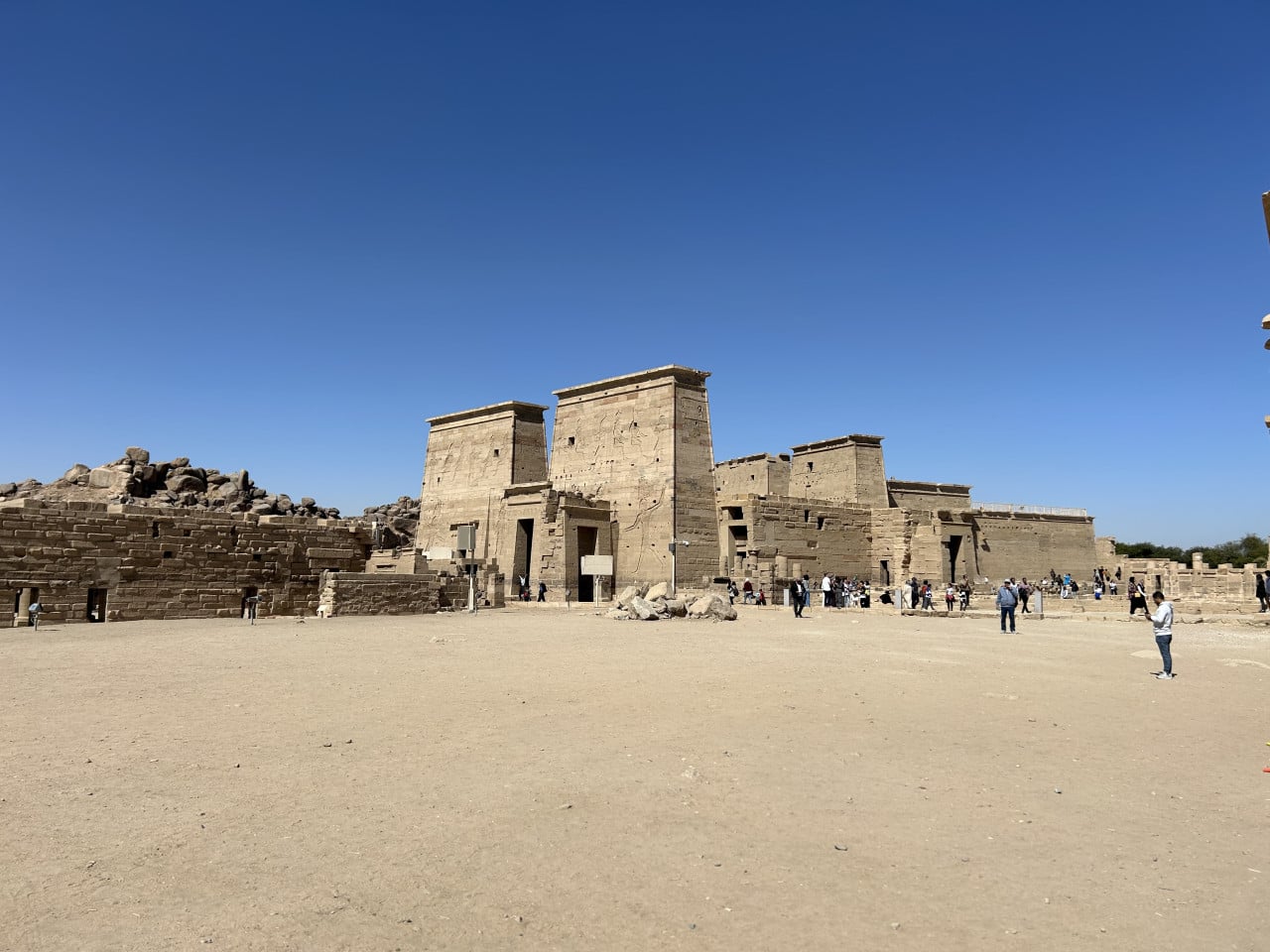 Chrámový komplex Philae s pískovcovými ruinami a turisty pod modrou oblohou