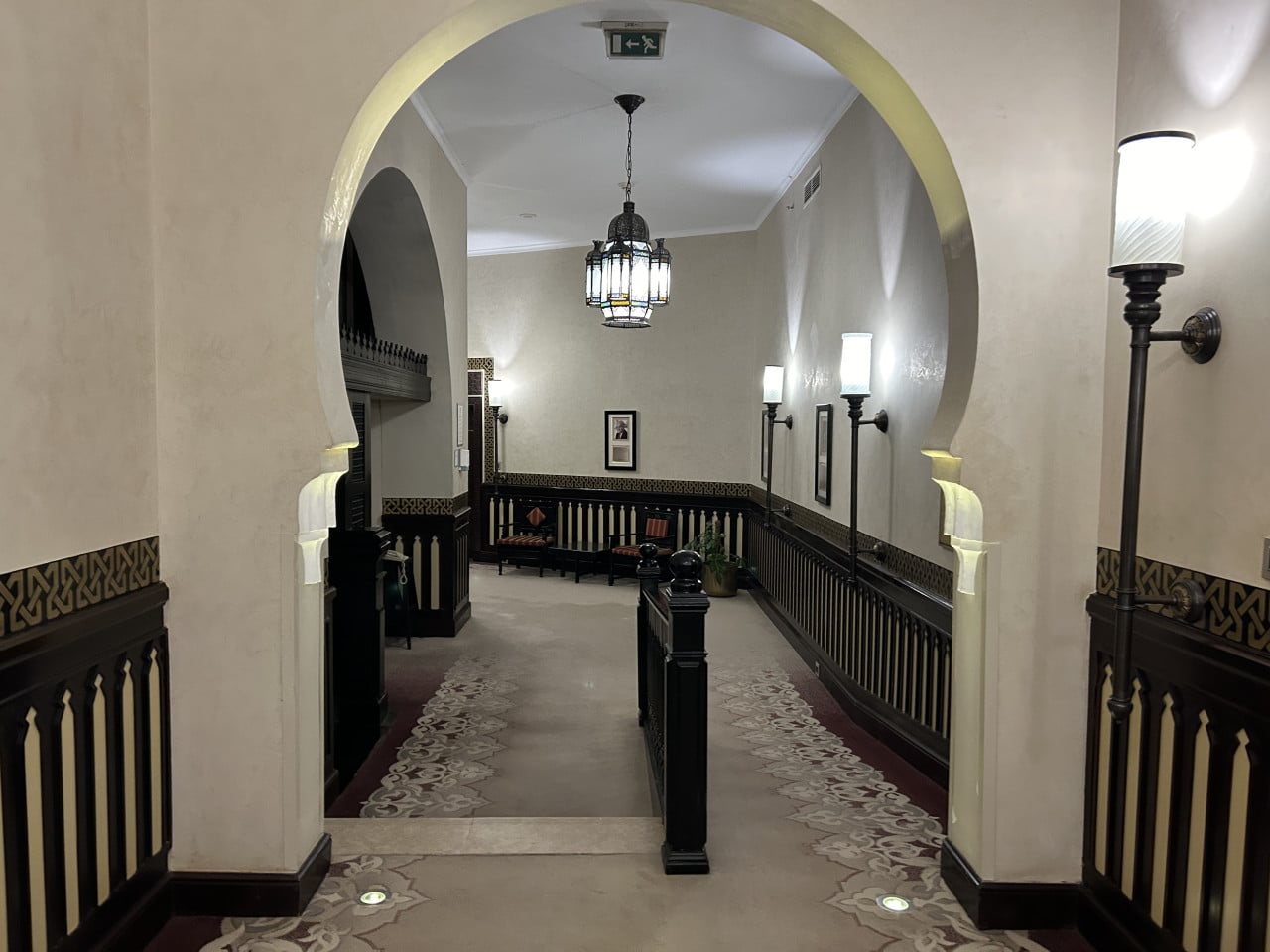 Elegantní hotelová chodba s oblouky, závěsným lustrem a arabskými lampami.