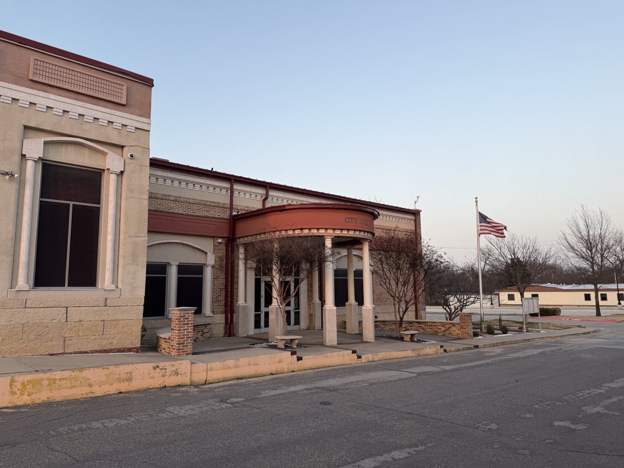 Budova radnice CITY HALL s kolonádou a americkou vlajkou u prázdné ulice.