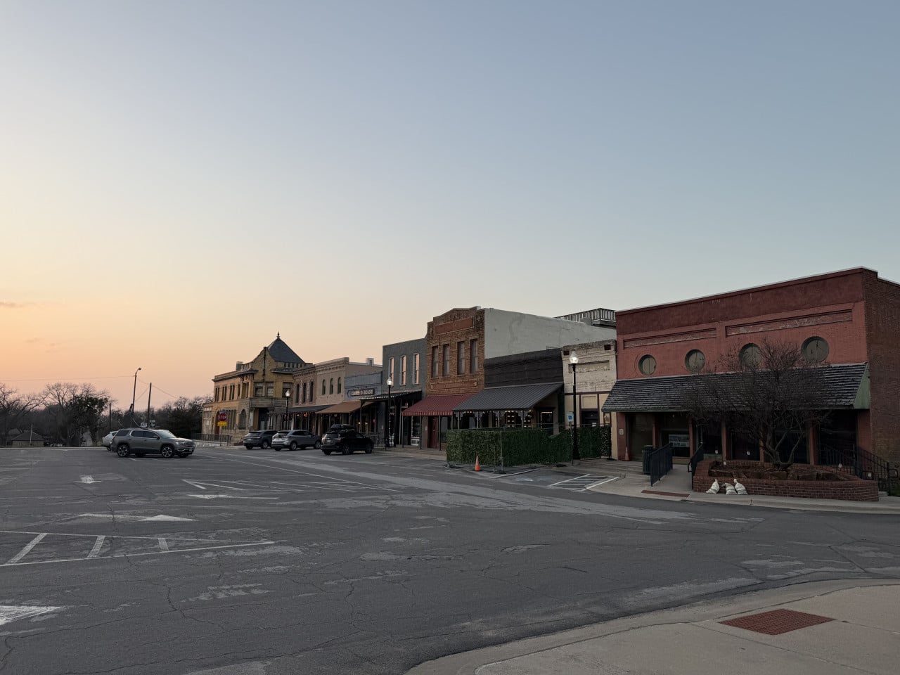 Hlavní ulice Pilot Pointu: historické cihlové domy, zaparkovaná auta, značka STOP za soumraku